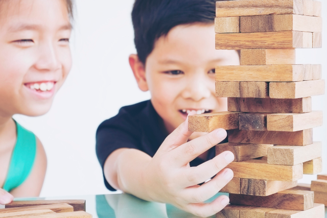 Children are playing a wood blocks tower game for practicing their physical and mental skill